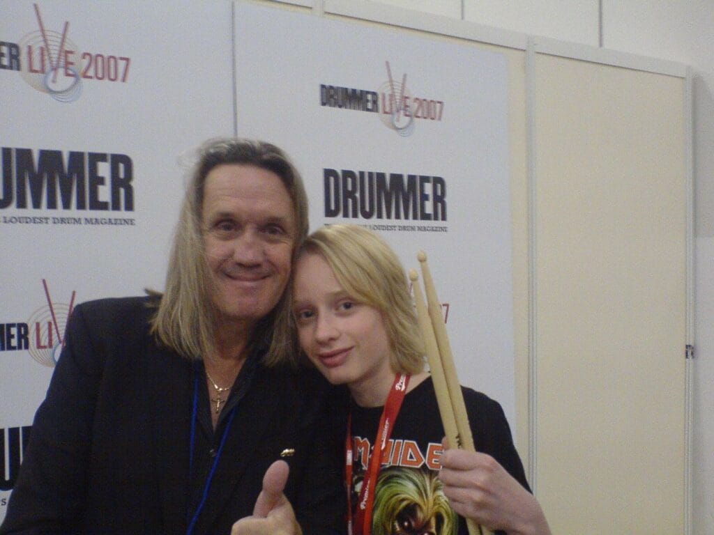 Gord and Nicko McBrain holding a pair of drum sticks.